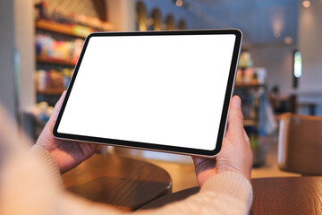 Mockup image of a woman holding digital tablet with blank white desktop screen in cafe