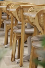 Row of Wooden Woven-Back Chairs in Cozy Café Setting with Light Modern Tables