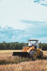 Obraz premium Rustic Outdoor Heavy Yellow Wheel Loader In Rural Landscape With Clouds