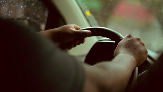 Homem negro dirigindo na chuva | Black hand on car steering wheel, close-up, safe driving