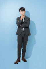 考える若いビジネスマン全身　水色背景