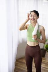 Smiling Japanese Woman Wiping Sweat with Towel After Workout