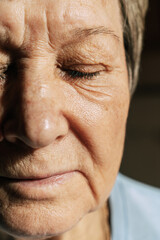 Close-up of elderly caucasian woman with closed eyes in natural light