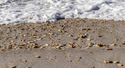 Sea foam washing up onto a pebbly beach.