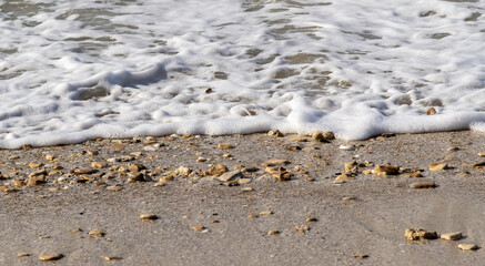 Sea foam washing up onto a pebbly beach.
