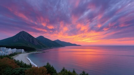 Vibrant Sunset Sky Over Coastal Mountains Reflecting In Calm Ocean With Distant Village Lights And Lush Greenery In The Foreground