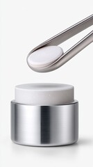 White Round Pill Being Held By Metal Tweezers Over a Metal Container In Studio Lighting