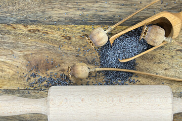 Poppy seeds and several dried poppy seed pods on wooden table