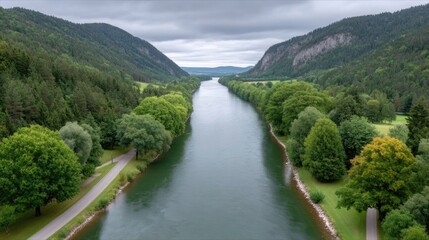 Wide Calm River Flows Through Lush Green Valleys Lined With Tall Pine Trees Under Overcast Skies With Distant Cityscape Visible