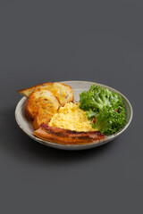 Traditional breakfast plate with scrambled eggs, Bacon, Sourdough and Salad.