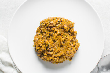 Overhead view of nigerian fried beans on a white plate, top view of nigerian stewed beans on a white background