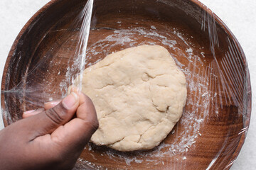 Overhead view of paratha dough being mixed in a wooden bowl, top view of flaky flatbread dough in a wood bowl, process of making paratha