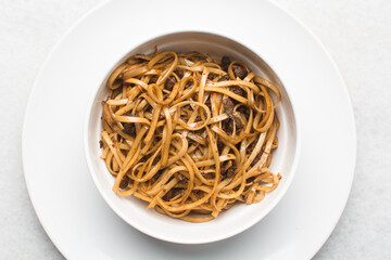 overhead view of fried egg noodles in a white bowl, top view of stir fried noodles in a bowl