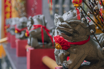 Stone foo dog guardian statue wearing red ribbon for good luck at chinese temple