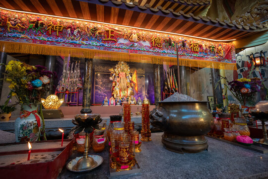 Golden chinese deity surrounded by smaller deities in a shrine