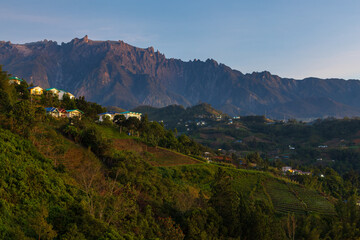 Mount Kinabalu dominating the skyline at dusk with colorful houses in the foreground