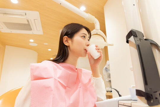 歯の背術後、口を濯ぐ女性