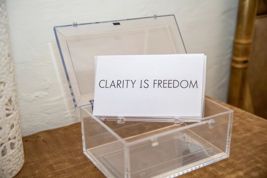 An open clear acrylic box holding cards with the inspirational phrase Clarity Is Freedom