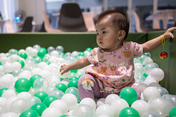 Fototapeta premium Adorable baby girl playing in a ball pit