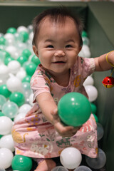 Obraz premium Adorable baby girl playing in a ball pit