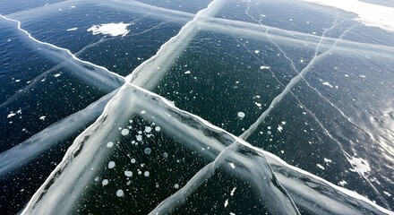 Cracked ice surface with trapped air bubbles and streaks of snow, forming geometric patterns.