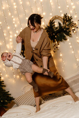 Mother and child having fun on the bed in Christmas interior.