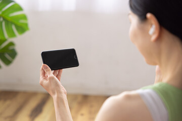 Close-up of Smartphone Held by Japanese Woman Wearing Wireless Earphones