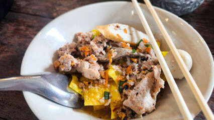 Thai spicy noodle soup with minced pork and crispy fried wontons, traditional Tom Yum noodle dish