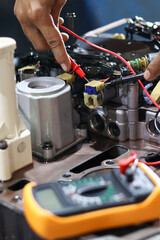 Hands of a technician using a multimeter to check the wiring and solenoid components of an automatic transmission valve body during diagnostic testing and repair.