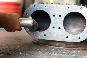 Worker using a pneumatic die grinder with an abrasive wheel to smooth and polish the rough surface...