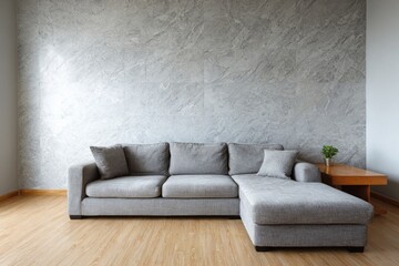 Gray sectional sofa placed against a marble textured wall.