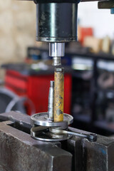 Crankshaft component being pressed by a hydraulic press during engine assembly or repair, emphasizing mechanical force and precision in the workshop.