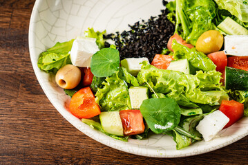 Colorful Greek salad displayed beautifully on a white plate with fresh ingredients and herbs