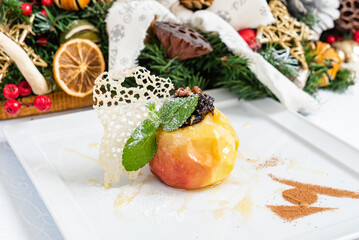 A beautifully baked apple sits on a Christmas table, surrounded by festive decorations and treats