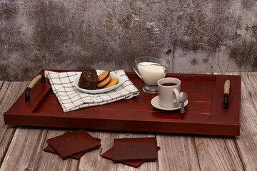 wooden breakfast tray with coffee, milk and pastries, on a wooden table