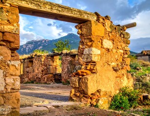 Sunlit ruins of stone structures, mountains in background