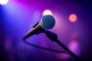Obraz premium A microphone is positioned in the foreground with a vibrant, colorful light display in the background, suggesting a lively music performance atmosphere. Generative AI.