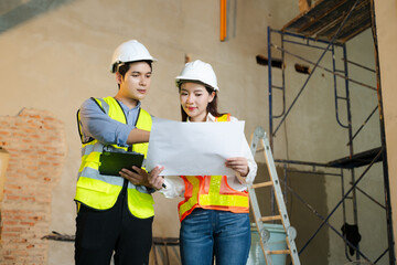 Asian architects and engineers planning construction project with blueprints, laptop, and teamwork...