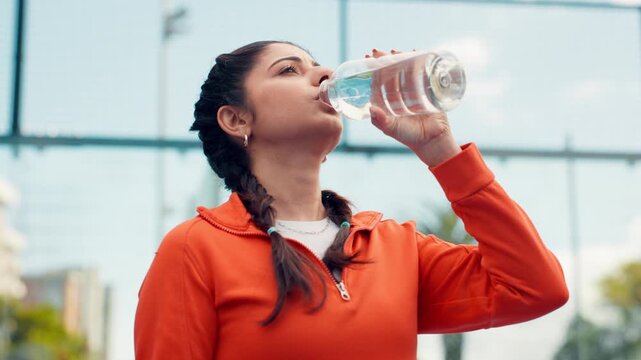 Fitness, woman and drinking water on court with bottle for sports hydration, workout or exercise break. Active, female person and thirsty in city with beverage for wellness, electrolytes or recovery.
