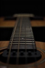 Close up on intricate vintage guitar strings and fretboard, bathed in warm, diffused sunlight on a wooden surface. A macro shot focusing on the strings and fretboard of a vintage acoustic guitar. The