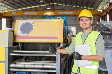 A Smiling Asian industrial engineer in safety gear giving a thumbs-up while holding a tablet/clipboard, standing by a heavy roll forming machine.