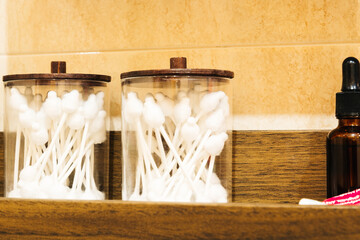 Cotton swabs inside jars on a wooden shelf