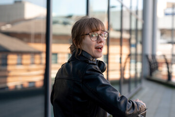Fototapeta premium Young woman enjoying a sunny day near modern glass buildings while riding a bicycle in the city