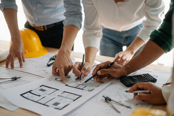 Two colleagues discussing data working and tablet, laptop with on on architectural project at construction site at desk in office