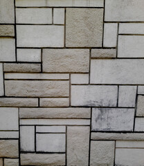 Close-up view of a decorative stone wall with rectangular textured tiles in neutral colors