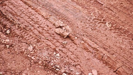Tire tread marks in dried mud, pattern on a dirt road.