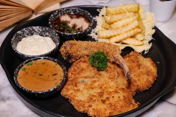 Delicious Fried Pork Chops with Side Dishes Served on a Black Plate