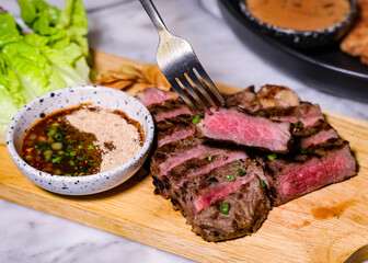Juicy, grilled steak with sauce on a wooden board ready to be enjoyed