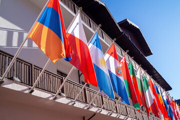 Diverse flags displayed on a balcony against a clear blue sky in a vibrant setting
