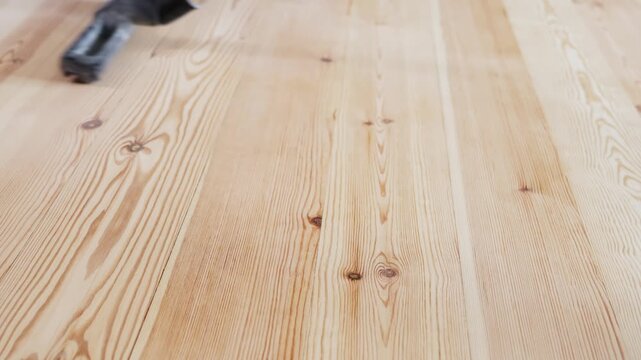 Cleaning scene showing vacuum cleaner working over natural hardwood flooring with prominent wood grain pattern capturing everyday household maintenance and interior care techniques